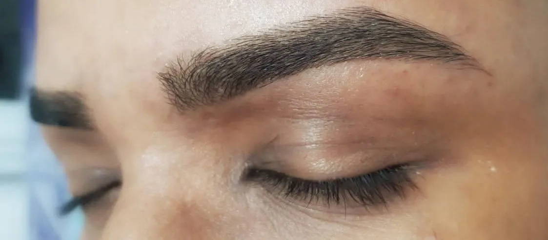 Close de sobrancelha feminina modelada, com fios alinhados e desenho definido, resultado de design de sobrancelhas